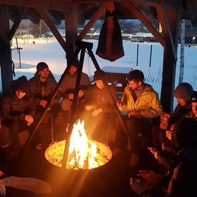 Group of students socialising by a fire in the outdoors in Norway 